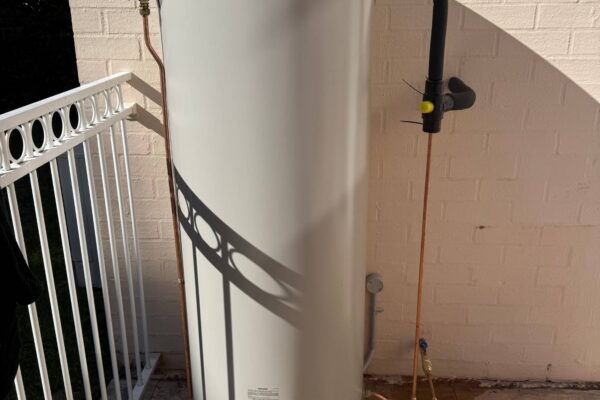 Newly installed Rinnai Hotflo electric storage hot water system mounted against a brick wall by JRA Plumbing Services