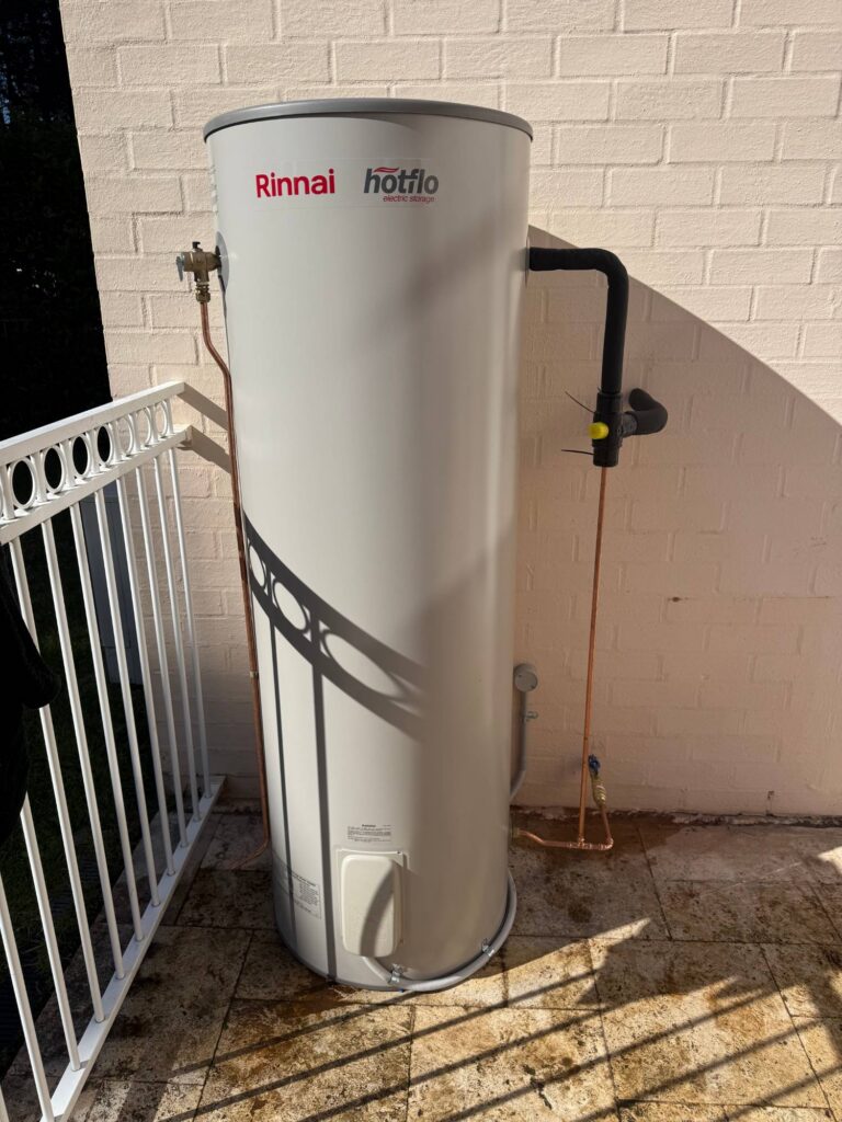 Newly installed Rinnai Hotflo electric storage hot water system mounted against a brick wall by JRA Plumbing Services